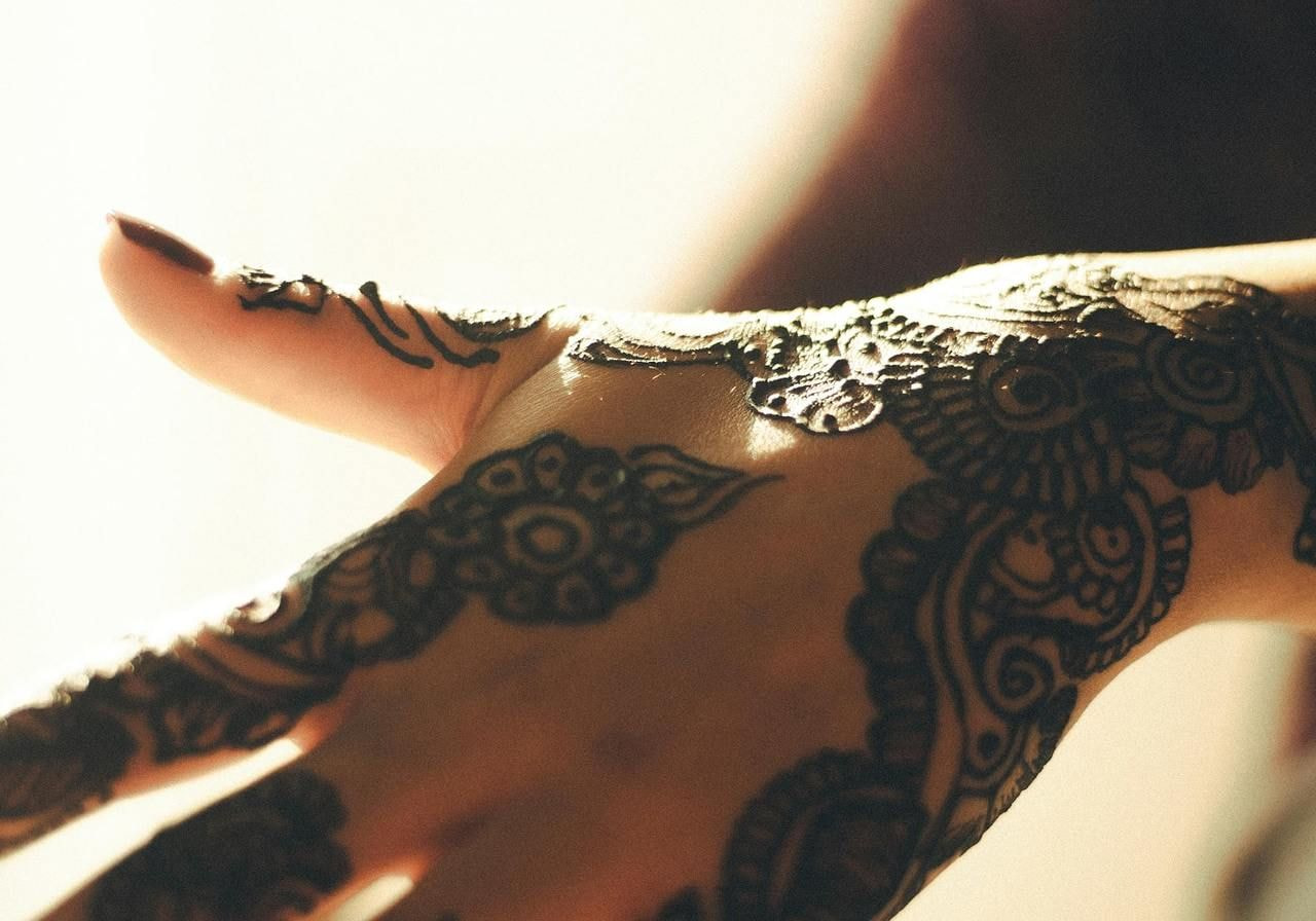 A close-up of a woman's hand adorned with intricate henna designs on her skin.